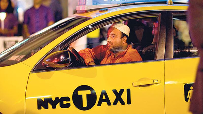 Driver at the wheel of a yellow NYC taxi