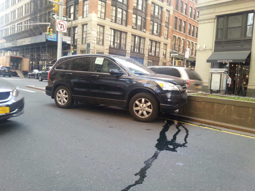 Black SUV parked on a cracked Manhattan street