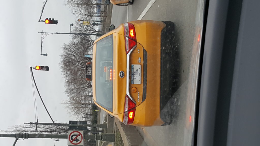 Rear of a yellow taxi seen from a passing car