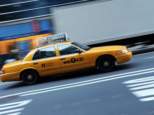 Yellow NYC taxi driving along a city street